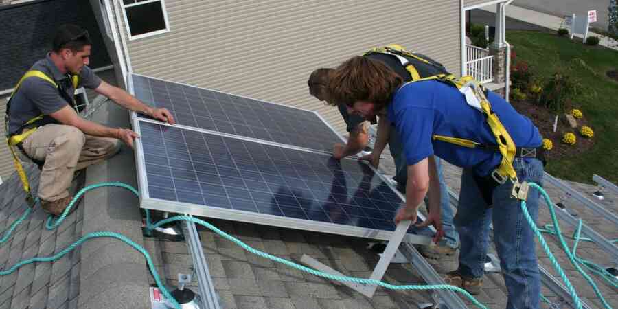 Workers on residential roof installing distributed solar panels