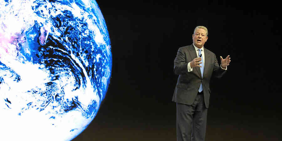 Al Gore speaking on stage at World Economic Forum in front of and image of Earth as seen from space